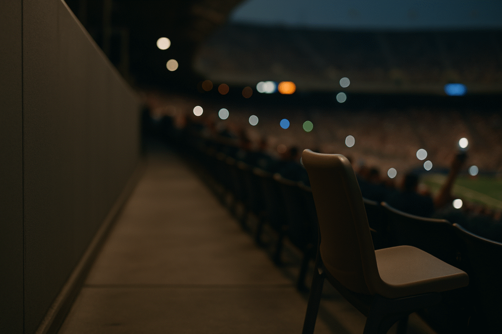 Empty stadium seat turned toward the aisle with blurry camera lights glowing in the background, creating a sharp and humorous sense of consequence.
