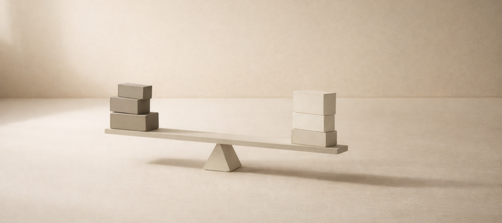 Minimalist editorial still life showing a subtly unbalanced structure, symbolizing economic comparison, tradeoffs, and disciplined evaluation.